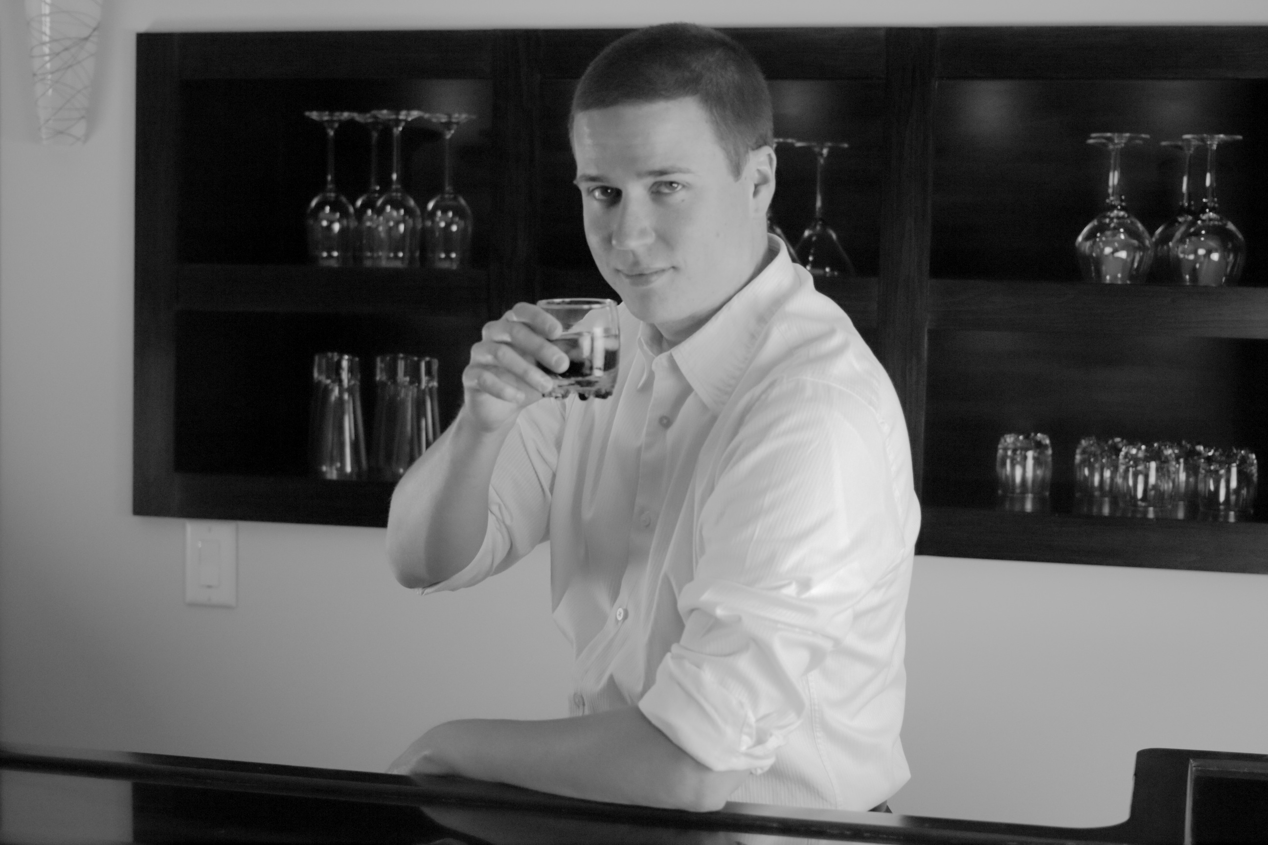 The author stands behind a bar wearing a formal white shirt
           with the collar unbuttoned and the sleeves rolled up. As his
           eyes meet the camera, he smirks and hoists a tumbler half full
           of dark liquid.